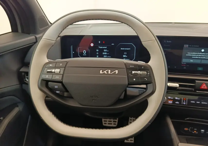 Vue intérieure centrée sur le volant bicolore gris clair et noir du Kia Sportage 2026 avec tableau de bord numérique.