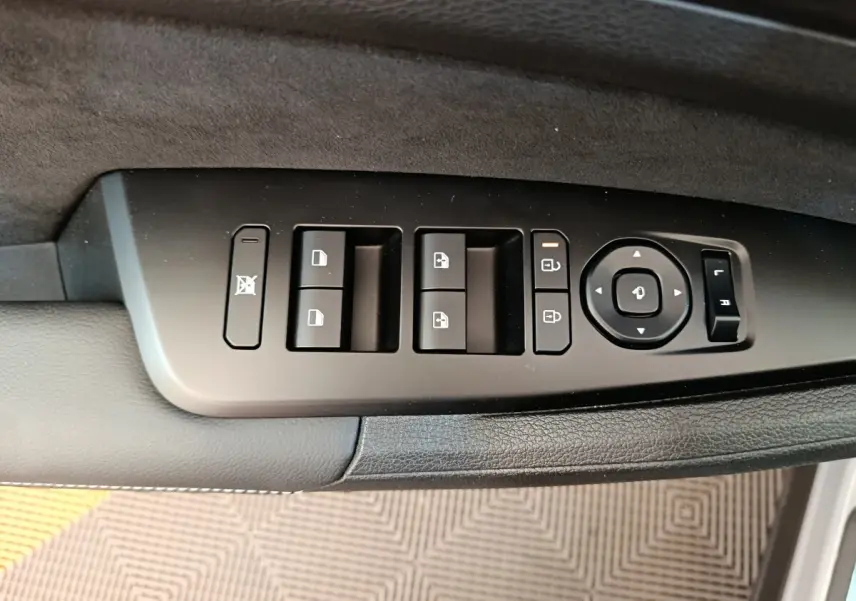 Gros plan sur les commandes de lève-vitres et rétroviseurs côté conducteur du KIA Sportage gris clair 2026.