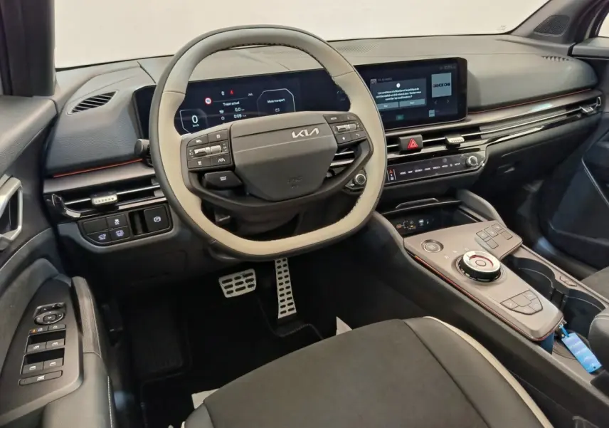 Intérieur avant du Kia Sportage 2026, vue du poste de conduite avec volant bicolore et écran tactile central.