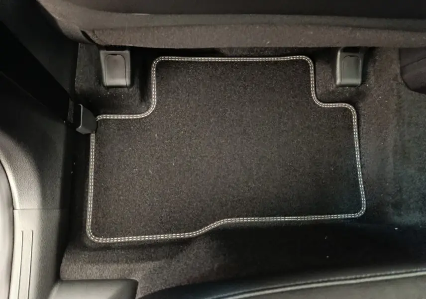 Tapis de sol noir avec surpiqûres blanches côté passager arrière du Kia Sportage gris clair 2026.