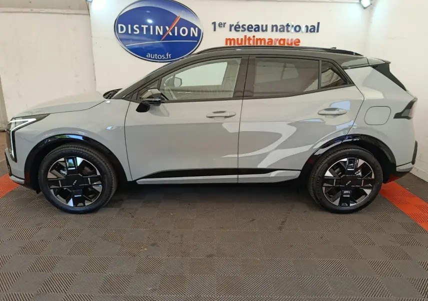 Vue de profil côté gauche du KIA SPORTAGE gris clair avec jantes noires et toit noir contrasté.