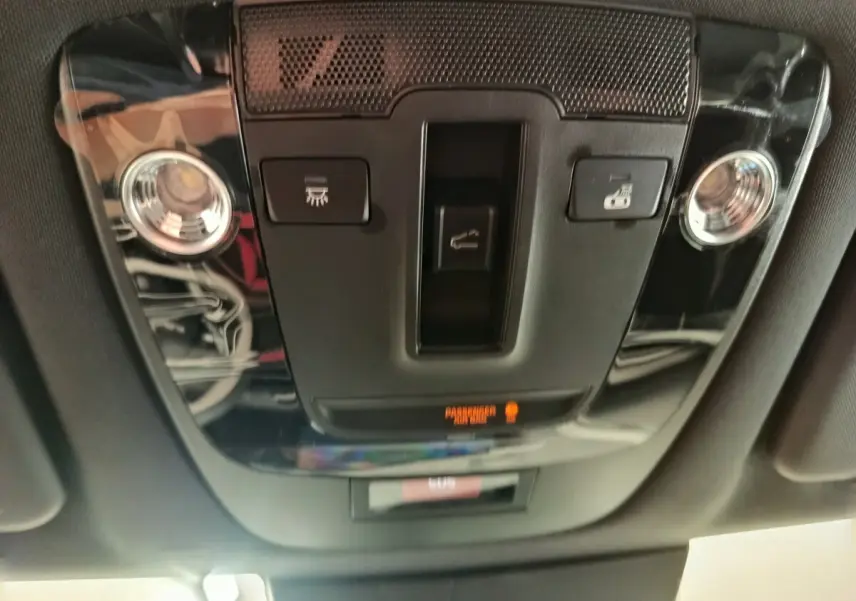 Vue en gros plan du plafonnier intérieur noir brillant du KIA SPORTAGE 2026 avec commandes d’éclairage et alerte passager.