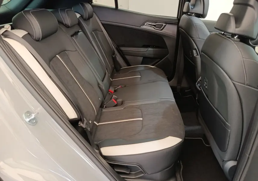 Vue intérieure côté gauche des sièges arrière gris foncé et noir avec surpiqûres blanches du Kia Sportage 2026 gris clair.