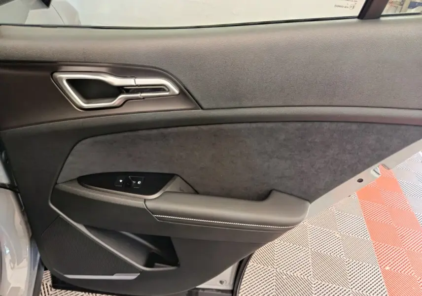 Gros plan sur la porte intérieure côté gauche du Kia Sportage 2026, avec garniture noire et poignée argentée.