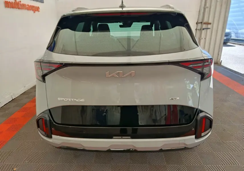 Vue arrière d’un KIA Sportage gris clair avec bande noire distinctive et feux arrière LED modernes.