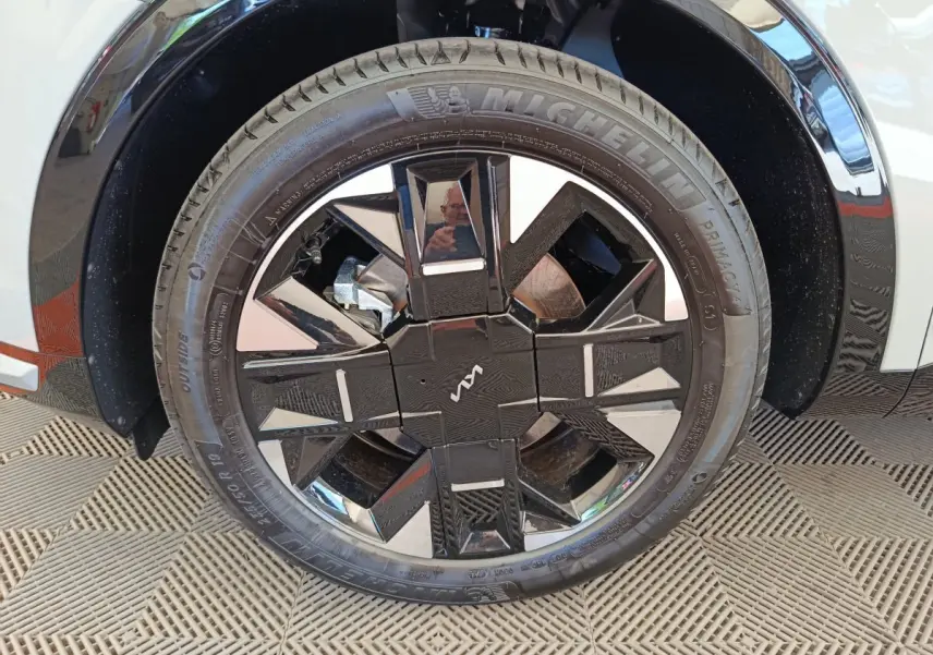 Gros plan sur la roue avant droite du KIA Sportage gris clair, avec jante noire au design géométrique distinctif.