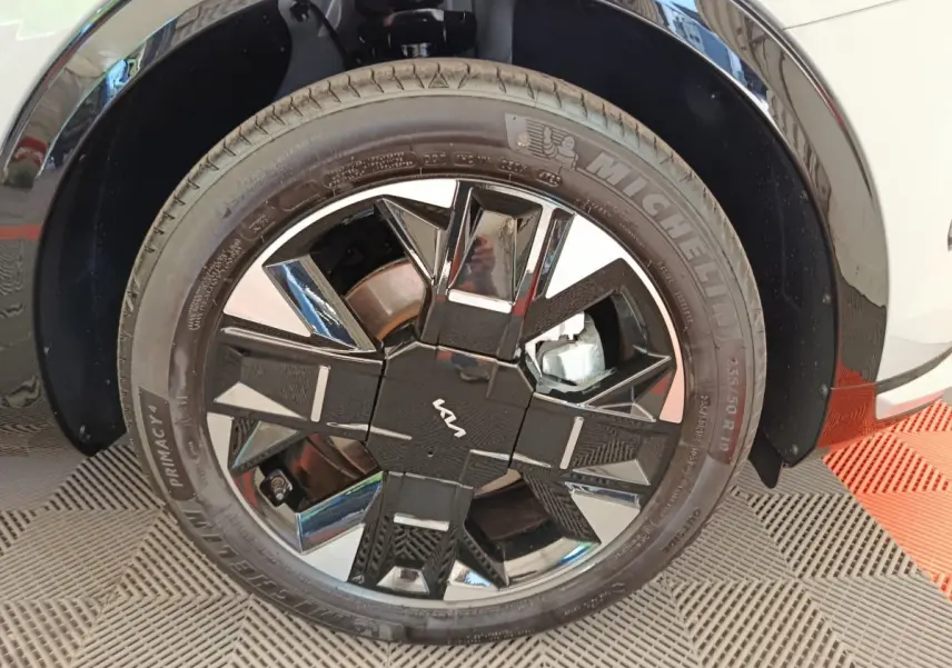 Gros plan sur la roue avant droite du Kia Sportage gris clair avec jante noire et argentée au design géométrique.