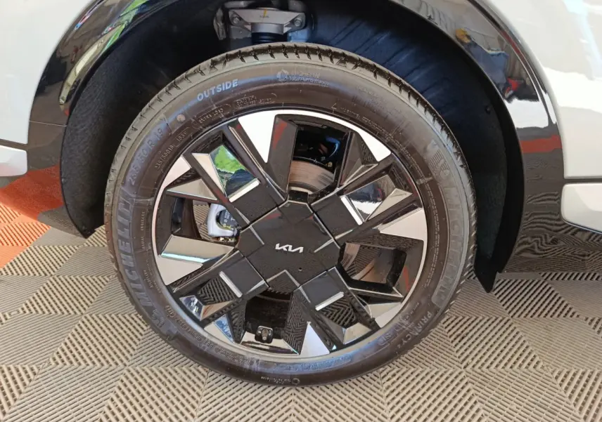 Gros plan sur la roue avant droite du KIA Sportage gris clair, mettant en valeur la jante noire et argentée au design géométrique.