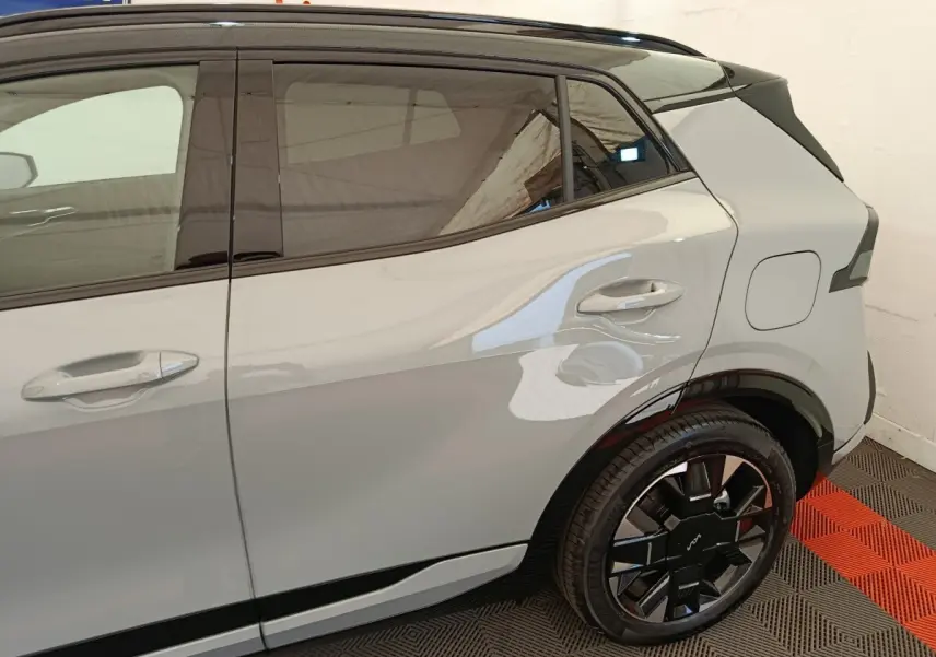 Vue côté droit arrière du Kia Sportage gris clair, mettant en valeur la porte arrière et la roue au design moderne noir brillant.