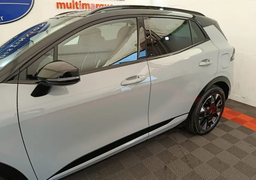 Vue latérale droite du Kia Sportage gris clair 2026 avec rétroviseur noir brillant et jante au design moderne.