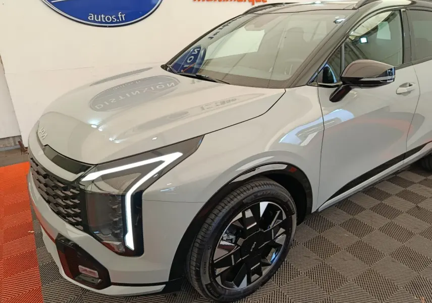 KIA SPORTAGE gris clair en 3/4 avant droit, avec phares LED en forme de L et jantes noires distinctives.