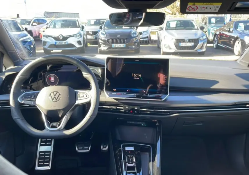 Vue intérieure avant de la Volkswagen Golf noire 2026, avec volant sport, écran tactile central et pédalier aluminium.