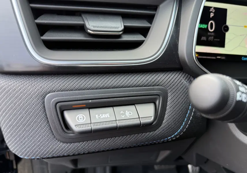 Gros plan sur les commandes E-SAVE et réglage des phares du tableau de bord du Renault Captur noir étoile 2025.
