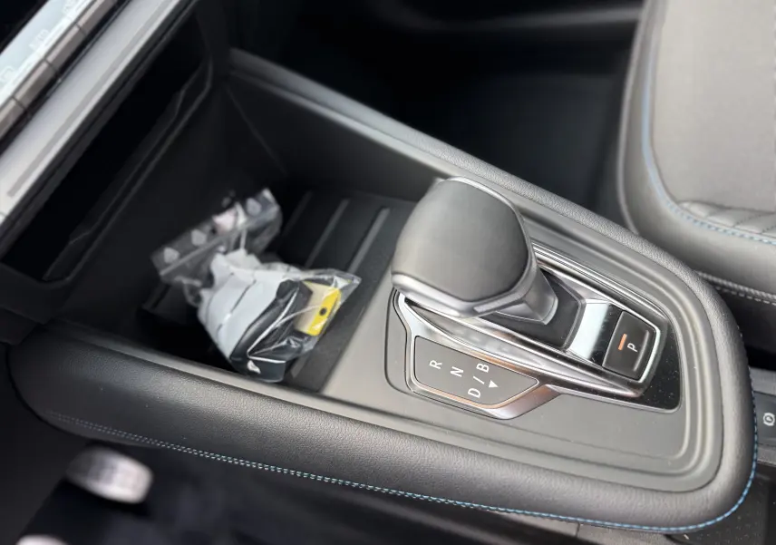 Le levier de vitesses automatique noir du Renault Captur 2025, avec surpiqûres bleues sur la console centrale.