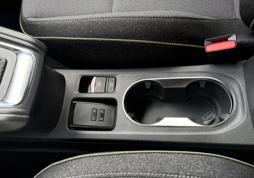 Gros plan sur la console centrale noire du Renault Captur gris Rafale, avec porte-gobelets et commandes électriques.