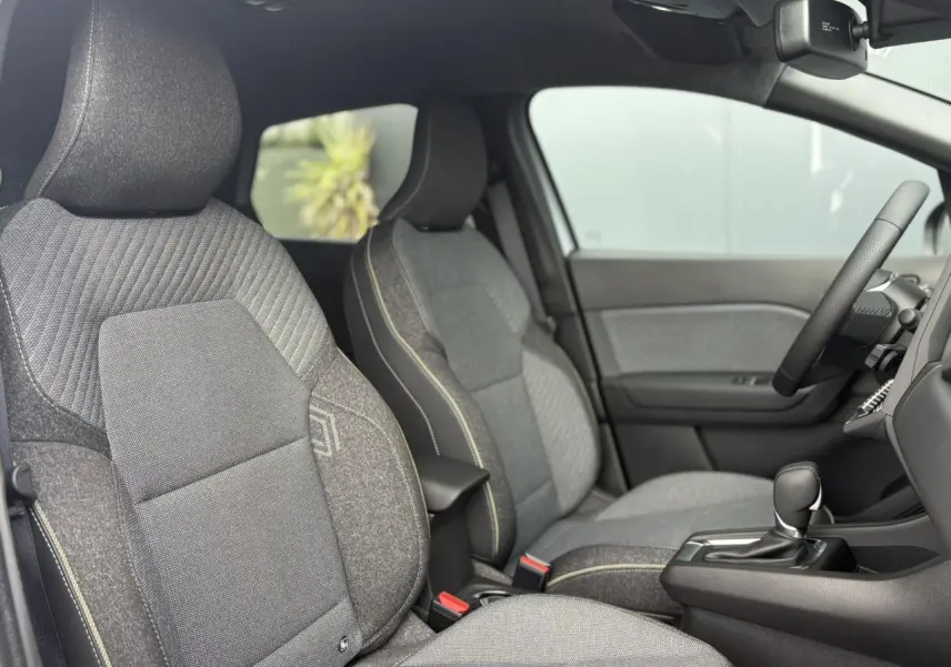 Intérieur Renault Captur 2025, vue côté gauche sur sièges gris texturés et console centrale avec levier de vitesse.