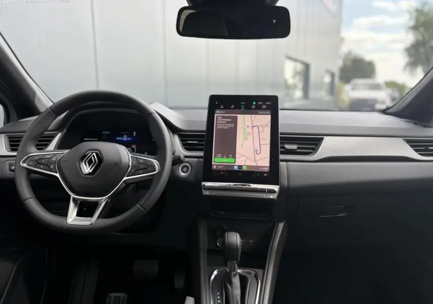 Intérieur du Renault Captur 2025 vu de face, tableau de bord noir avec écran tactile central et volant multifonction.