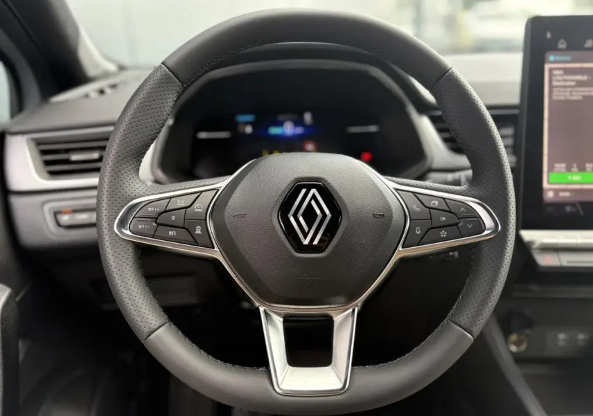 Volant en cuir perforé avec commandes intégrées du Renault Captur 2025, vue frontale centrée sur le logo Renault.