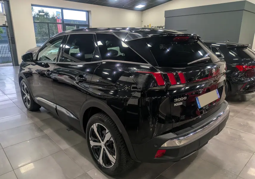 Vue 3/4 arrière droite du Peugeot 3008 noir Perla avec feux arrière à griffes et jantes bi-ton en showroom.