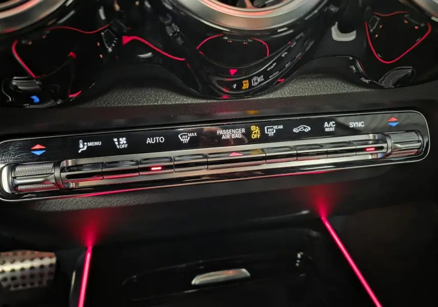 Détail de la console centrale du Mercedes GLB 200 d AMG Line 2022 avec éclairage d'ambiance rouge et commandes climatisation digitales.