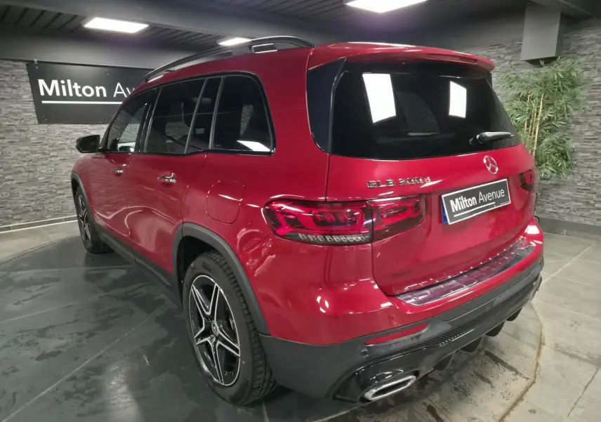 Vue 3/4 arrière droite d'un Mercedes GLB 200 d AMG Line rouge Patagonie avec jantes AMG noires et baguettes chromées.