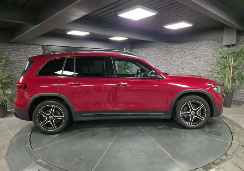 Vue de profil côté gauche d'un Mercedes GLB 200 d AMG Line rouge avec jantes AMG 19 pouces noir et argent.