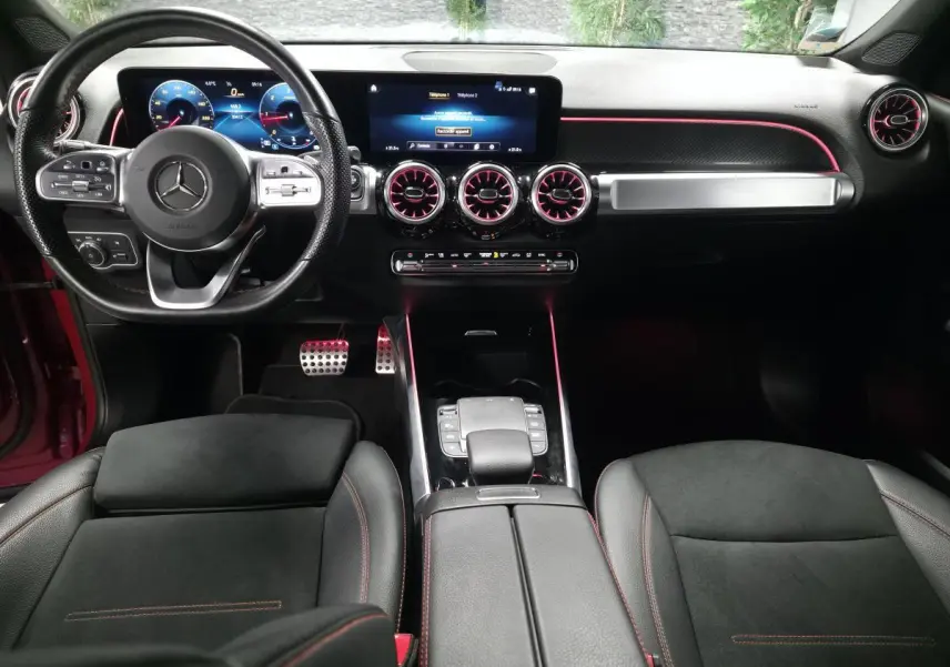 Vue intérieure avant du Mercedes GLB 200 d AMG Line 7 places, avec éclairage d'ambiance rouge et instrumentation digitale.