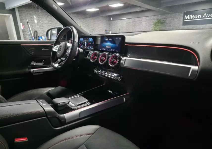 Intérieur du Mercedes GLB 200 d AMG Line 7 places, vue côté conducteur avec éclairage d'ambiance rouge et tableau de bord digital.