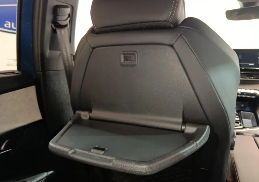 Détail de la tablette rabattable noire sur le dossier du siège avant droit du Peugeot 5008 GT bleu 2023.