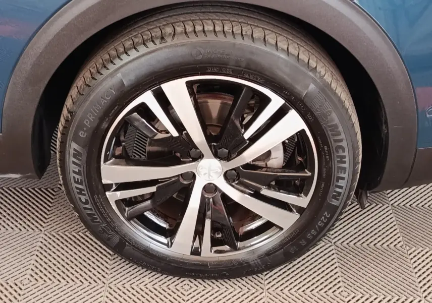 Gros plan sur la roue avant droite du Peugeot 5008 bleu 2023 avec jante alliage bicolore et pneu Michelin.