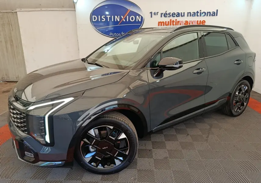 KIA Sportage 2026 gris foncé en 3/4 avant droit, avec phares LED verticaux et jantes noires distinctives.