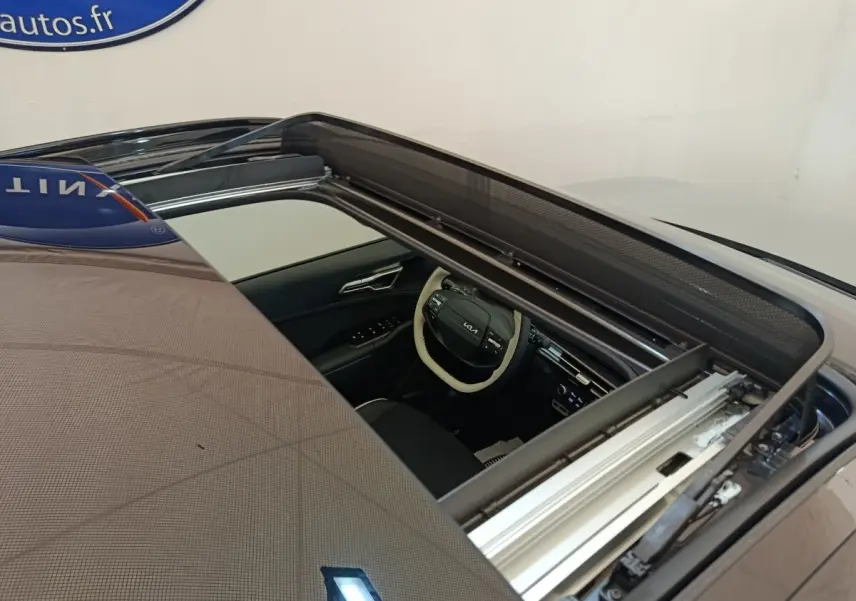 Vue plongeante sur le toit ouvrant panoramique ouvert du Kia Sportage gris foncé, avec aperçu intérieur côté conducteur.