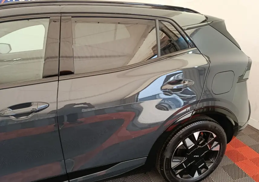 Vue latérale arrière droite du Kia Sportage gris foncé, mettant en valeur la jante noire au design moderne.