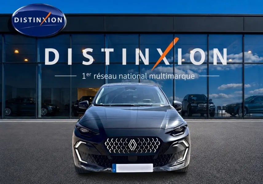 Vue frontale d'une Renault Clio VI noire garée devant une vitrine avec logo Distinxion en arrière-plan.
