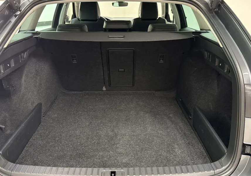 Coffre ouvert d'une Skoda Octavia Combi gris graphite 2023, vue arrière montrant un grand espace de chargement vide.