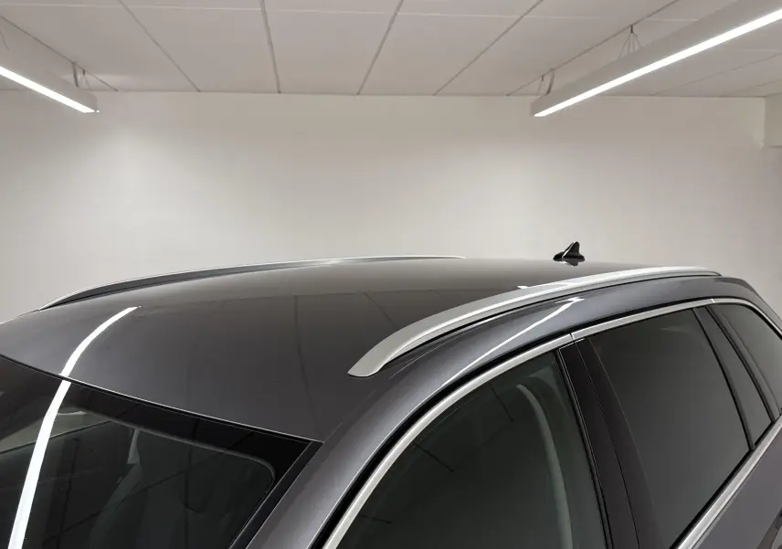Toit panoramique et barres de toit visibles sur le côté droit d'une Skoda Octavia Combi gris graphite 2023 en intérieur.