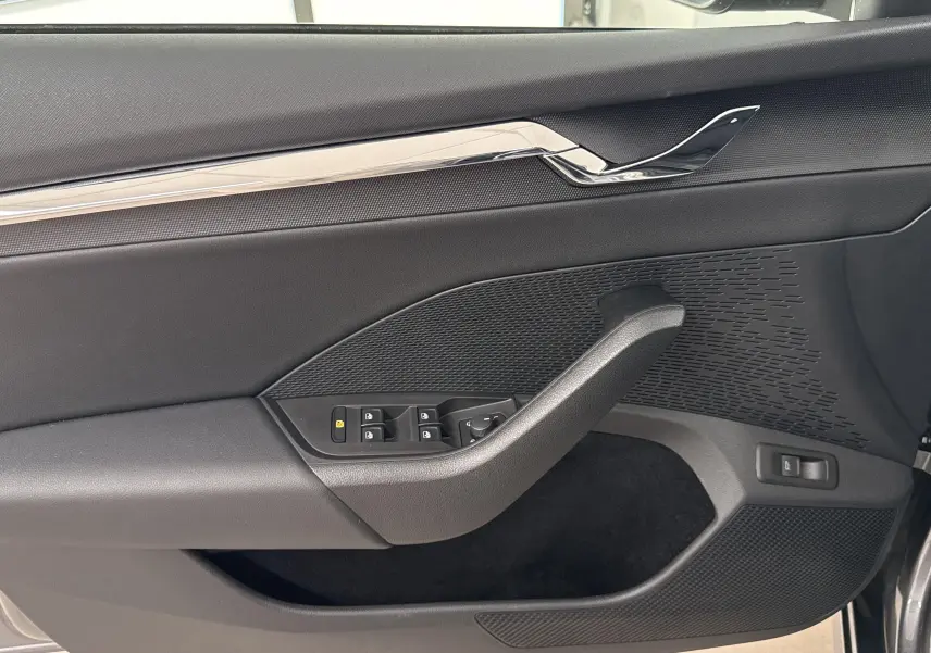 Vue rapprochée de la porte avant gauche gris graphite de la Skoda Octavia Combi 2023 avec commandes de vitres et poignée intégrée.