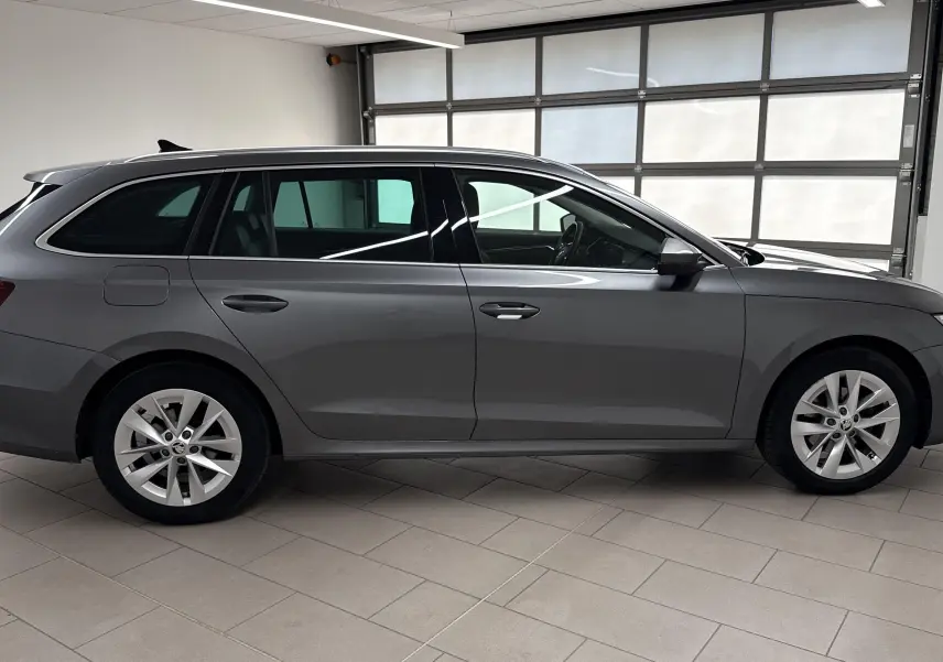 Skoda Octavia Combi 2023 gris graphite vue de profil côté gauche en intérieur avec jantes alliage.