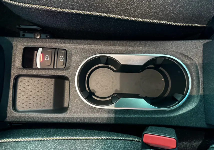 Gros plan sur la console centrale du Renault Captur 2025, avec porte-gobelets et bouton frein à main électrique allumé.