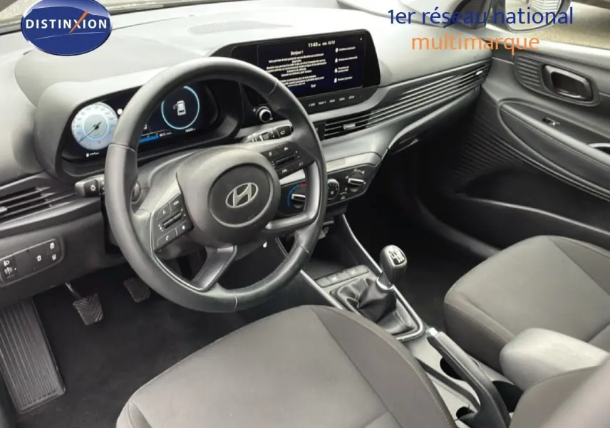 Intérieur noir de la Hyundai i20 2025, vue côté conducteur, volant cuir multifonction et tableau de bord digital.