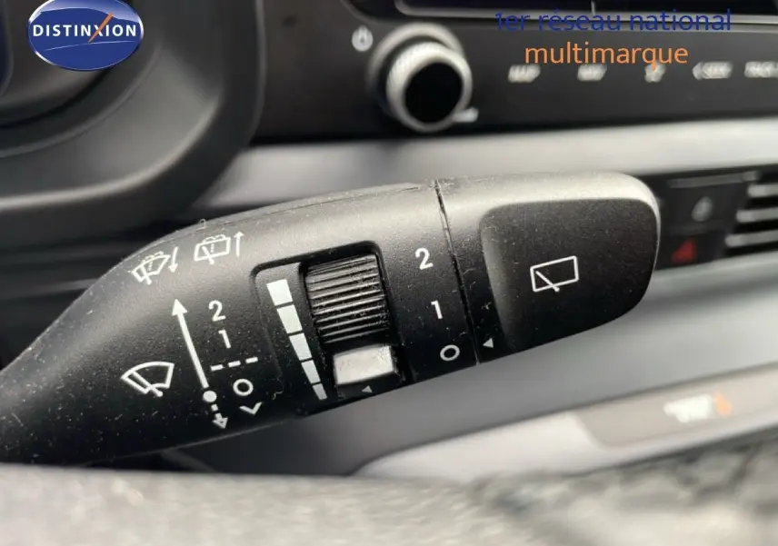 Gros plan sur la commande d'essuie-glace noire du Hyundai i20 2025, intérieur sombre avec détails blancs visibles.