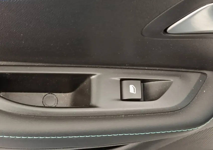 Gros plan sur la commande de lève-vitre côté porte intérieure d’une Peugeot 208 blanche, finition Allure Business.