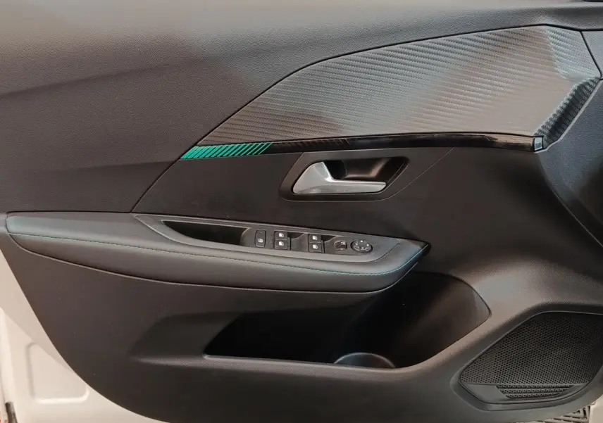 Intérieur côté gauche de la porte avant d’une Peugeot 208 blanche, avec garniture noire et insert décoratif gris texturé.