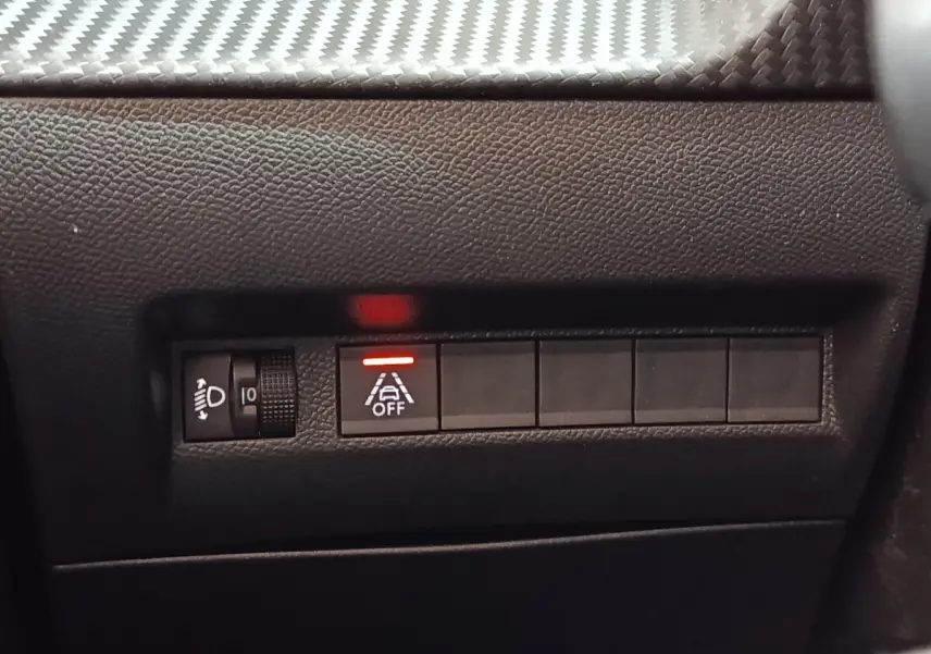 Détail intérieur du tableau de bord de la Peugeot 208 blanc, montrant les commandes d’éclairage et d’aide à la conduite.