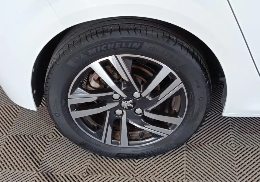 Gros plan sur la roue arrière droite d'une Peugeot 208 blanche avec jante alliage et pneu Michelin.