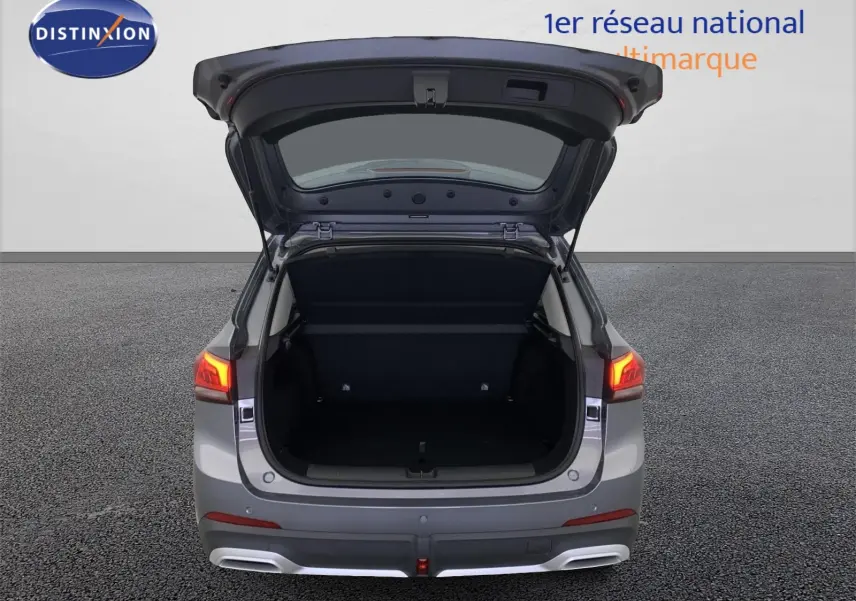 Vue arrière du MG ZS 1.5 L Hybrid+ gris Hampstead avec coffre ouvert et feux arrière allumés.