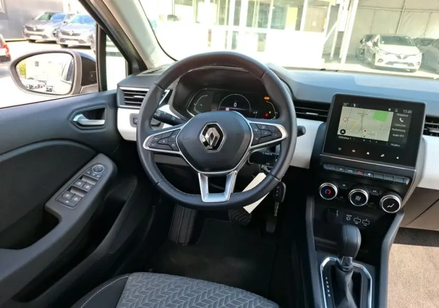 Vue intérieure avant de la Renault Clio 1.6 E-Tech gris clair, volant multifonction et écran tactile avec navigation visible.
