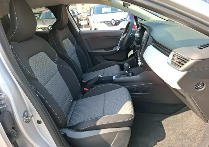 Vue intérieure côté gauche de la Renault Clio 1.6 E-Tech gris clair, avec sièges tissu bicolores et tableau de bord épuré.