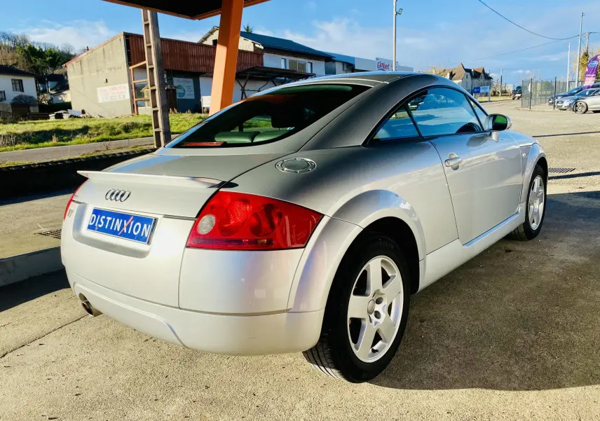 Audi TT Coupé gris vu en 3/4 arrière droit, soulignant ses feux rouges et jantes alliage 5 branches.