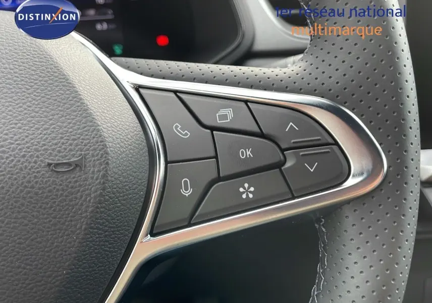 Gros plan sur les commandes au volant en cuir perforé du Renault Captur blanc nacré 2025, version hybride E-Tech.